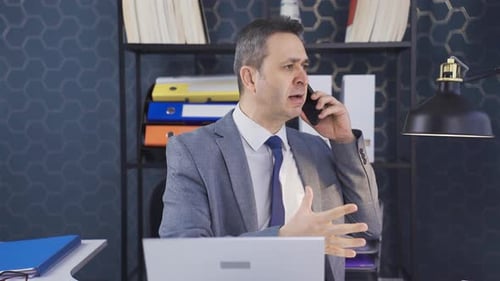 While talking about work problems on the phone in the office, he gets angry.