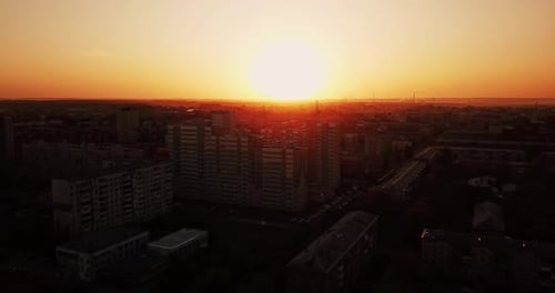 Drone view of sundown cityscape. Urban landscape against sunset aerial footage.