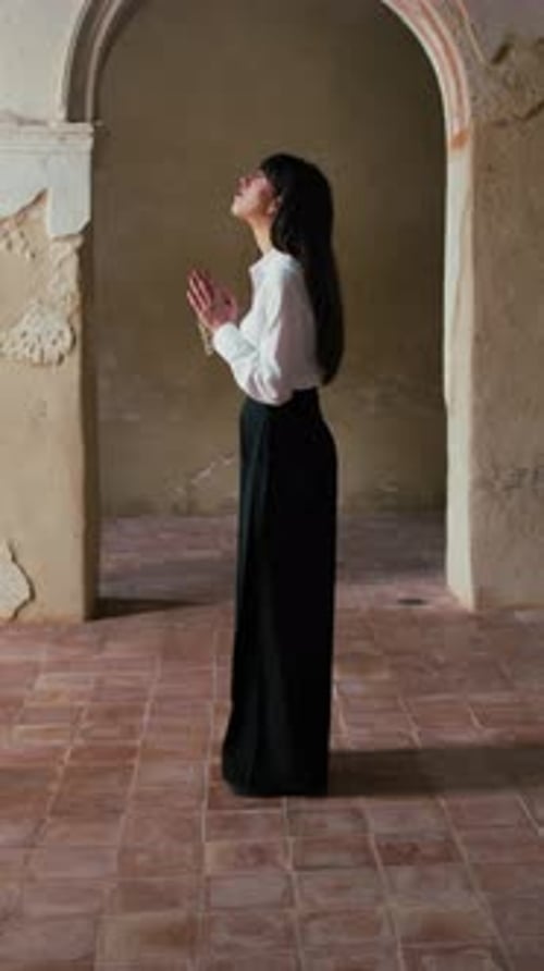 Woman Standing Still In The Middle Of An Old Church And Praying