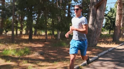 Young man sprinting intense workout on country road in forest, running athlete.