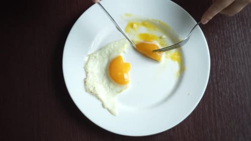 Finish Eating Fried Eggs. Male Hand Cutting Fried Egg With Knife And Fork. Closeup Shot Of Cuttin...