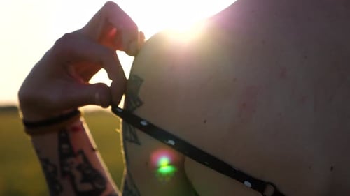 Close Up of Female Hand Taking Off Black Strap of Dress From Shoulder at Green Barley Meadow Arm of