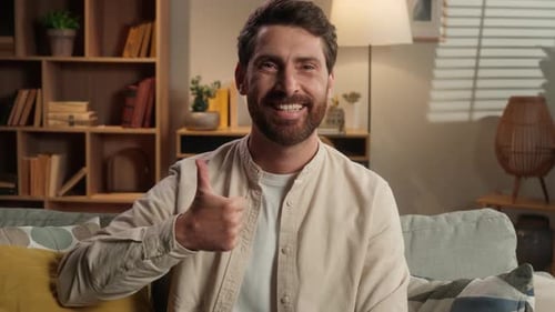 Man Smiles and Gives Thumbs Up on Couch