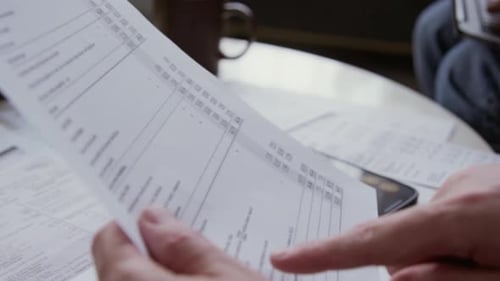 Man Reviews Financial Documents on Table at Home