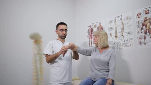A Therapist is Helping a Patient with Hand Exercises in a Clinic for Better Rehab Outcomes