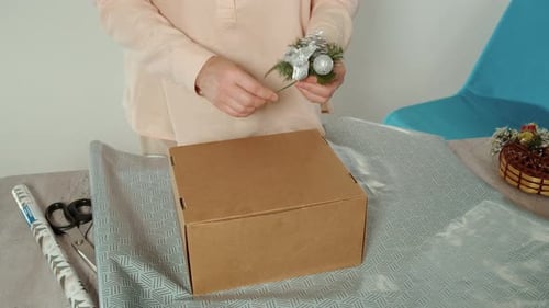 Woman Decorates Gift with Floral Ornament for Christmas