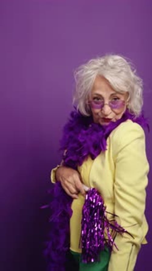 Femme âgée énergique dansant avec un boa à plumes violettes