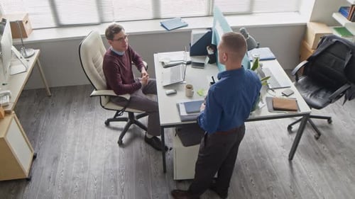 Two Male Colleagues Chatting during Work Discussion at Office