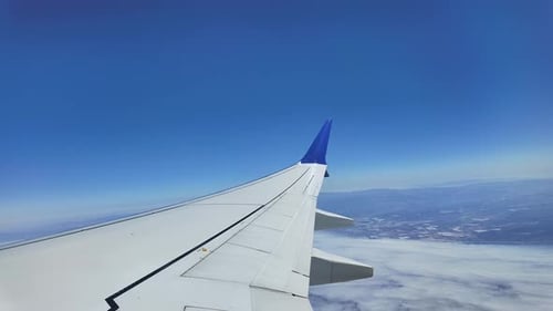 Timelapse of airplane wing view flying over light clouds