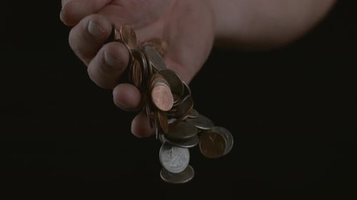Hand Pours Coins in Slow Motion on Black