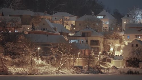 in a quiet Prague neighborhood at night, snow-covered trees and houses form a serene winter scene, w
