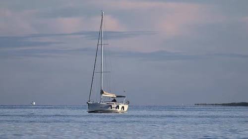 Ein einsames Segelboot, das friedlich auf ruhigem Meerwasser schwimmt, mit einem sanften Pastellhimmel und einer fernen Küste