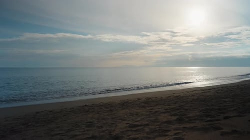 Panorama of the sea at sunset, mountains and the sun in the clouds.