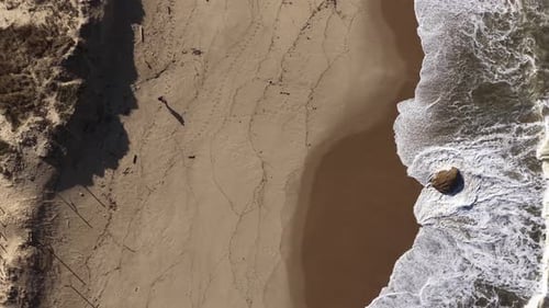 Vue aérienne d'un randonneur marchant sur la plage avec des vagues, Portugal.