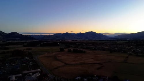 Small Town and Forest in Valley Against Large Mountains