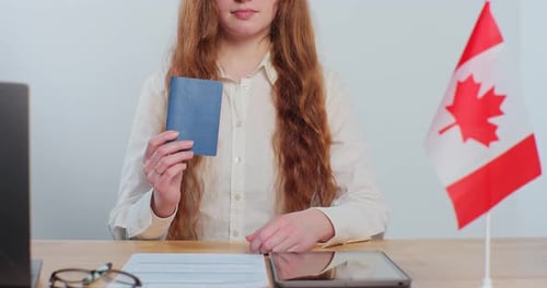 Woman Holding Canadian Passport at Desk