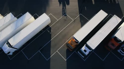 Moving Aerial Top View of Parked Semi Trucks with Cargo/ Refrigerator Trailers Standing on their De