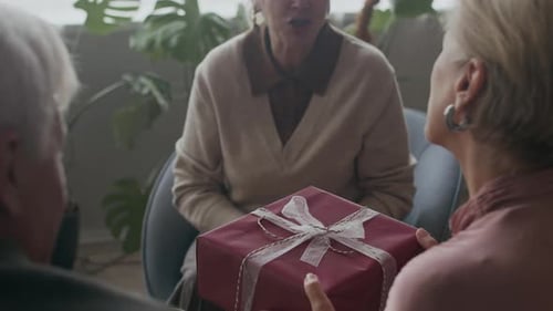 Senior Friends Exchanging Gifts in Living Room