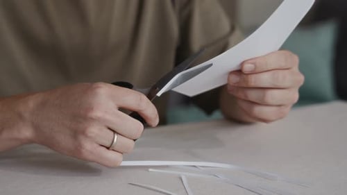 Hands Cutting Paper Strip with Scissors Close Up