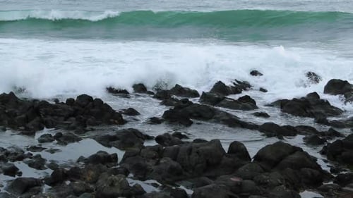 Close-up view of rocks offshore crashed by strong sea waves and reflecting on and across stones duri