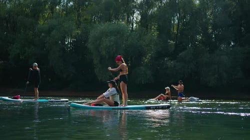 Group Of People Practicing Stand Up Boarding In River In Summer Day Sport And Leisure In Nature