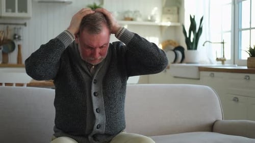 Senior Man Massaging Head in Bright Home