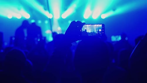 Enthusiastic Crowd Enjoys Concert Performance with Blue Lights