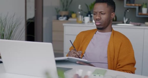 Young Adult Working on Laptop, Writing in Notebook