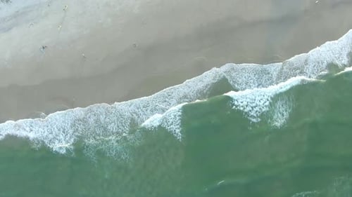 Aerial spinning drone view of sea waves breaking on sandy coastline. Aerial shot of golden beach mee