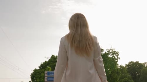Happy Blond Woman Smiles and Walks in City Park on a Sunny Day