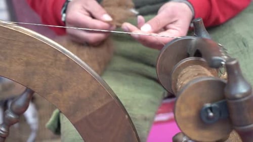 A street artist sewing manufacturing with traditional spinning wheel. Handcraft fiber sew by vintage