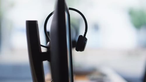 Empty Call Center Office with Headsets Resting on Computer Monitors Closeup