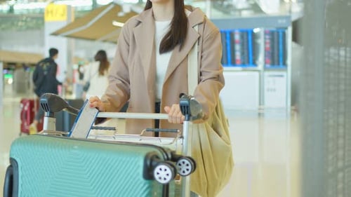 Asian young woman passenger checking departure boarding pass in airport.