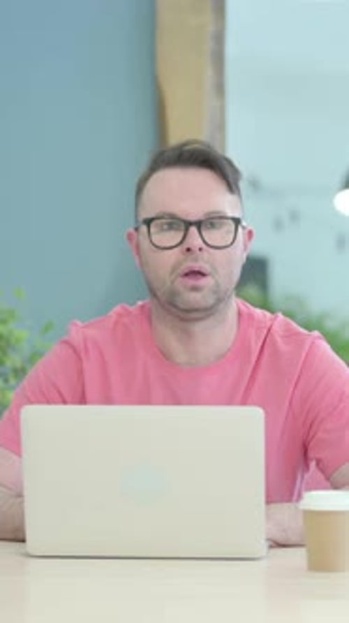 Man Smiles and Works on Laptop Indoors