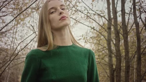 Modelo posando com vestido verde na floresta de outono