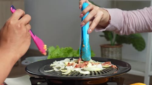 Preparing Korean Barbecue with Sizzling Meat and Onions