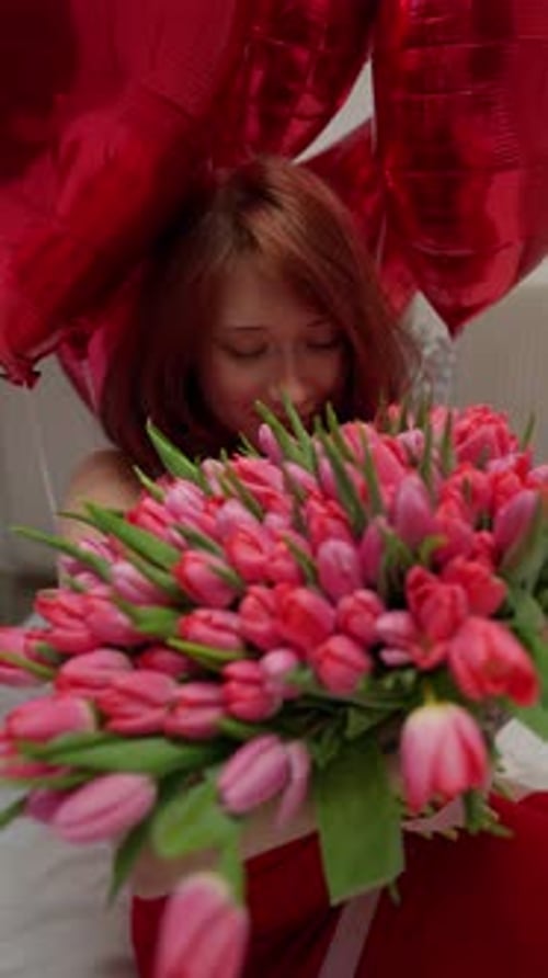 Smiling Woman with Flowers and Red Balloons Indoors