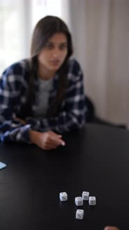 A Woman is Playing a Game with Dice on a Table Displaying Concentration and Engagement
