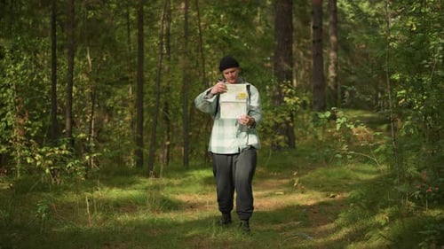 Traveler Reviews Route Details While Sun Filters Through Branches Male Forest Wanderer Carefully