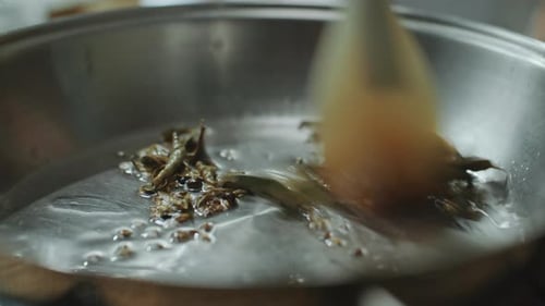 Close-Up of Stirring Indian Spices in Hot Oil in Frying Pan with Spatula