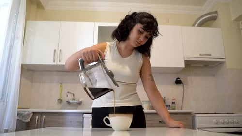 Woman Pours and Drinks Coffee in Kitchen