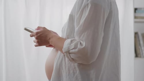 Pregnant Woman Uses Phone Indoors During Daytime