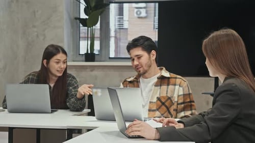 Des collègues assis autour de leur ordinateur portable discutent avec enthousiasme de leur projet commun et partagent