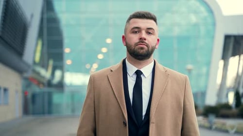 Close up portrait young handsome business bearded man smiling on urban background modern building