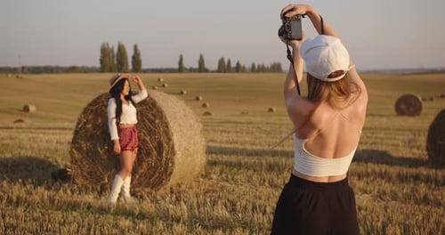 A Photographer Takes Pictures of a Model in a Field Near Haystacks