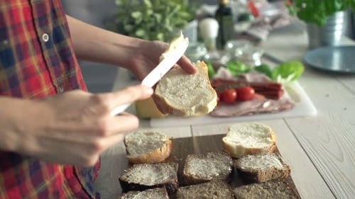 Woman Spreads Butter on Bread Slices in Kitchen