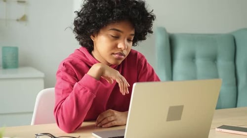 Sleepy African American Woman Sitting at Table with Laptop and Yawning