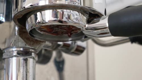 Espresso extracting and dripping closeup from a asked filter in slow motion