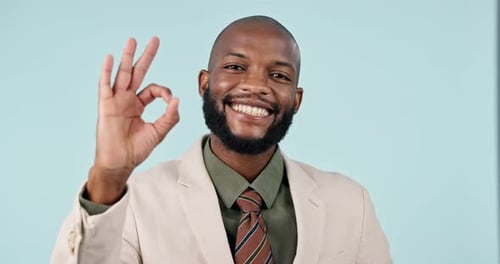Smile, ok and face of a black man on a studio background for perfect, support and feedback
