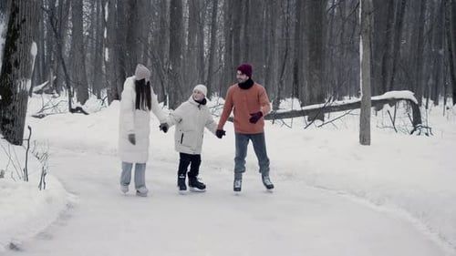 Ein älterer Bruder und eine ältere Schwester Hilfe ihrem jüngeren Bruder, Schlittschuhlaufen zu lernen, indem sie ihm die Hände halten